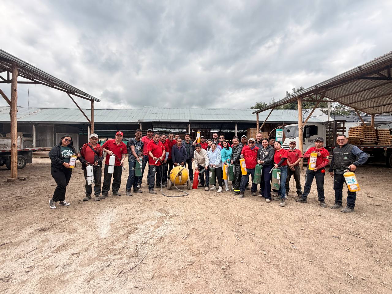 Grupo de trabajadores en capacitación práctica con extintores en entorno industrial