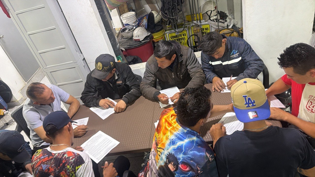 Grupo de trabajadores firmando documentos de seguridad industrial en inducción